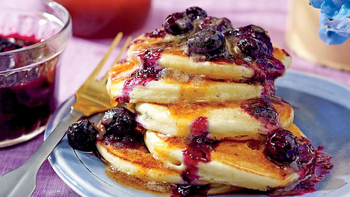 Ricotta Pancakes with Brown Butter-Maple Syrup and Blueberry Compote. hands...