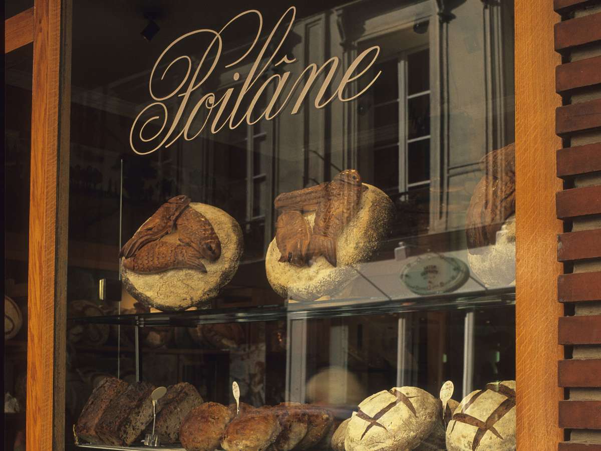 Bakery shop window with "Poilâne" written on it. Loaves of bread are visible inside